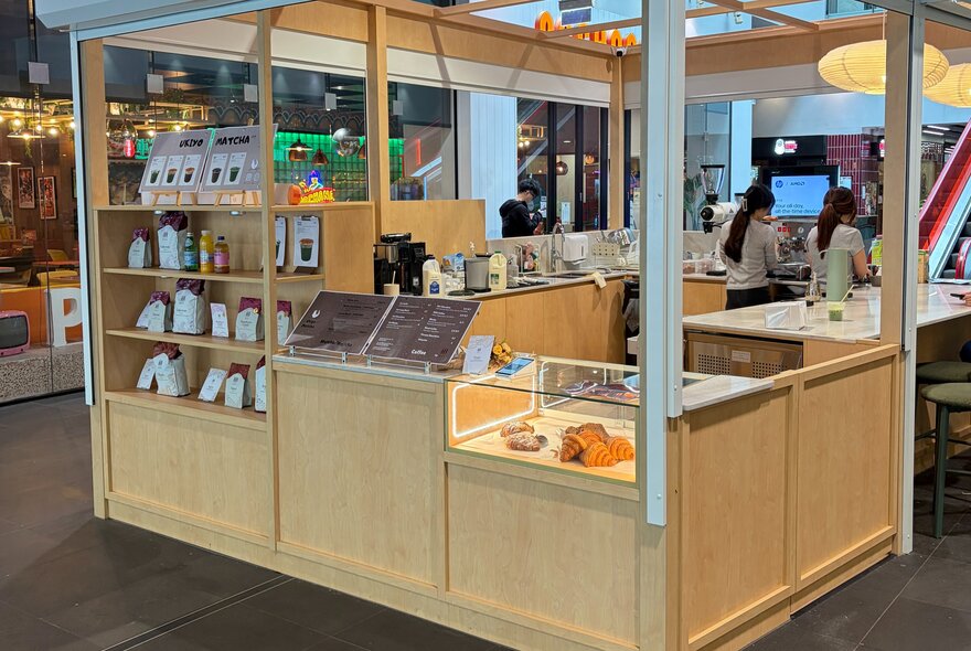 A pale timber booth in a shopping centre serving pastries and coffee.