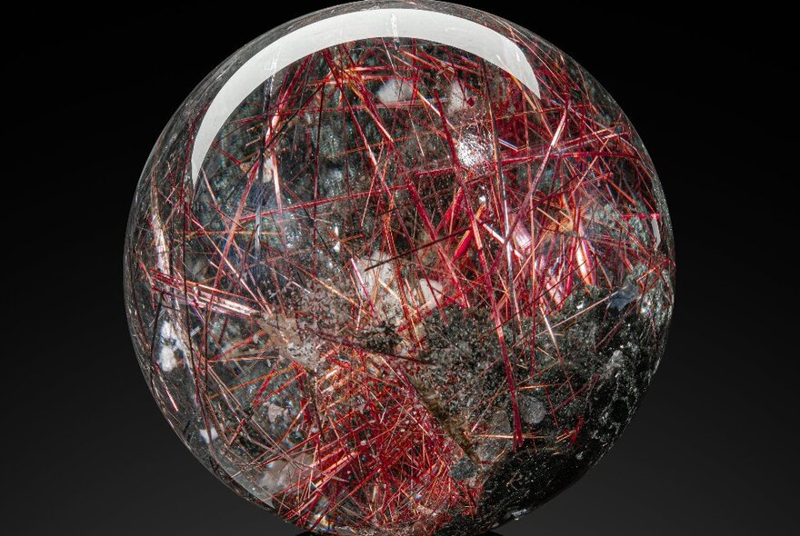 A crystal ball with internal red and black striations.