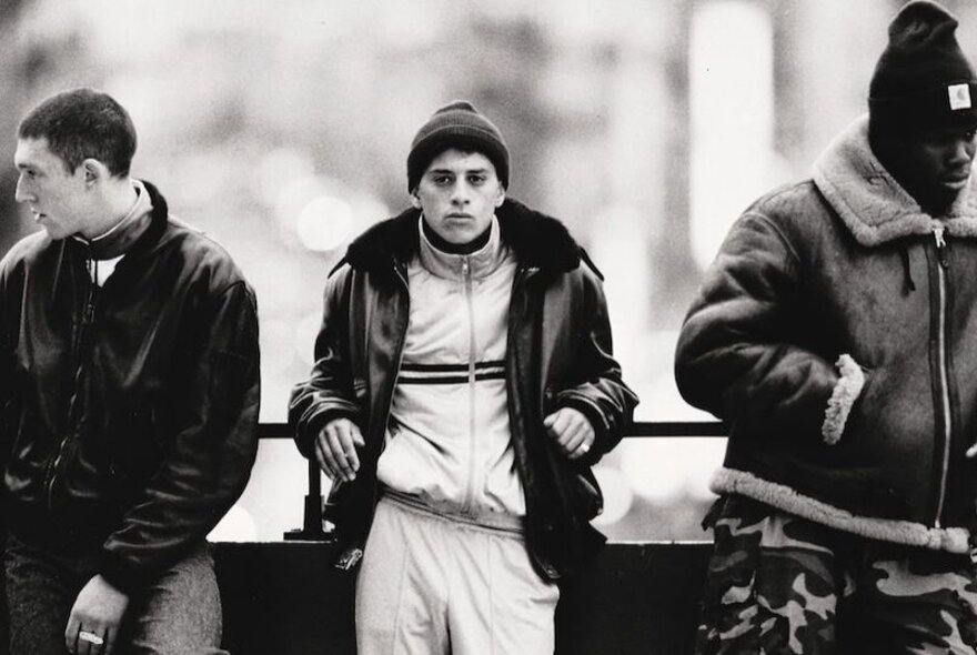 A still-frame from black and white French film, La Haine, depicting three youths loitering on a street.