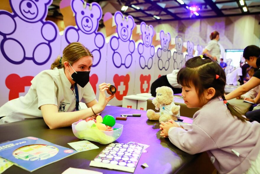 Children playing with toys and games at a table in a room decorated with teddy bears.