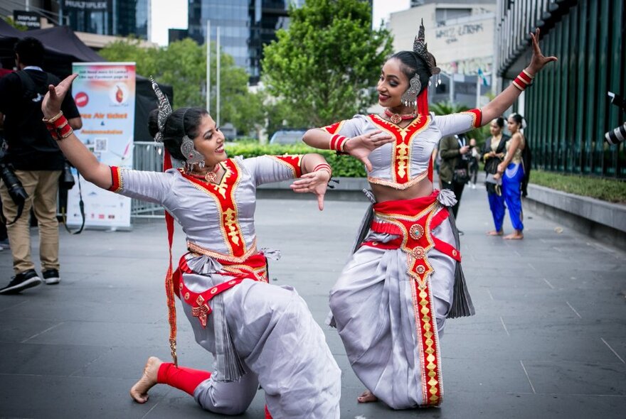 Two Sri Lankan traditional dancers in red and white costumes. 