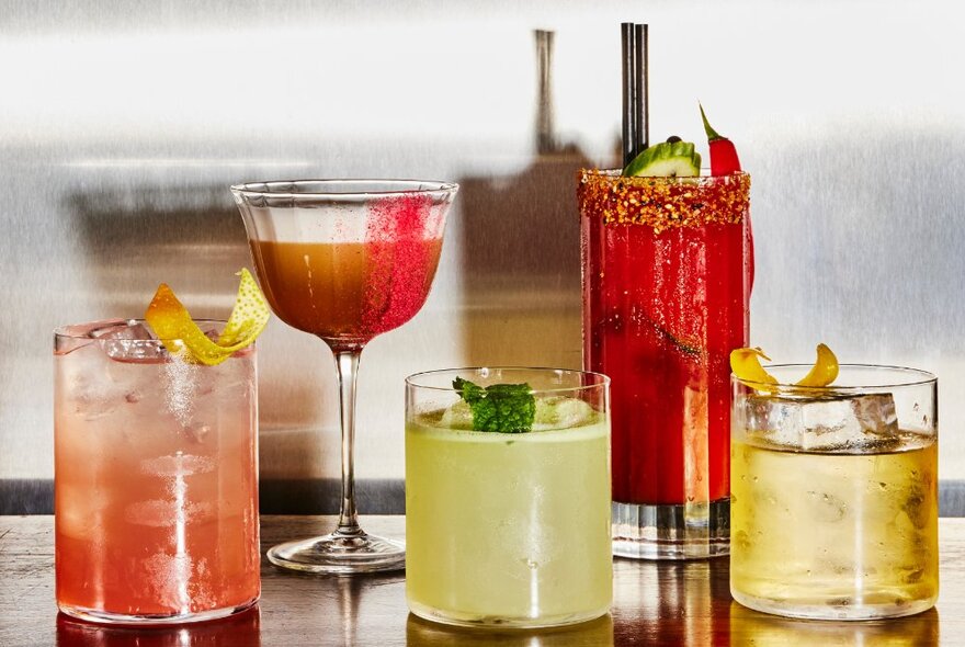 A selection of five cocktails in short, tall and champagne glasses.