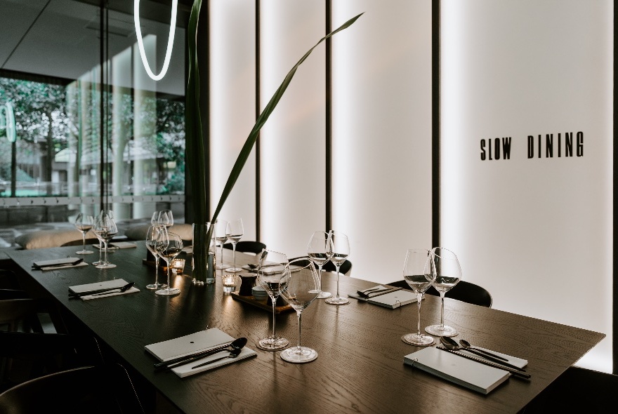 An empty dining space with a table set and a message saying 'slow dining' on the wall. 