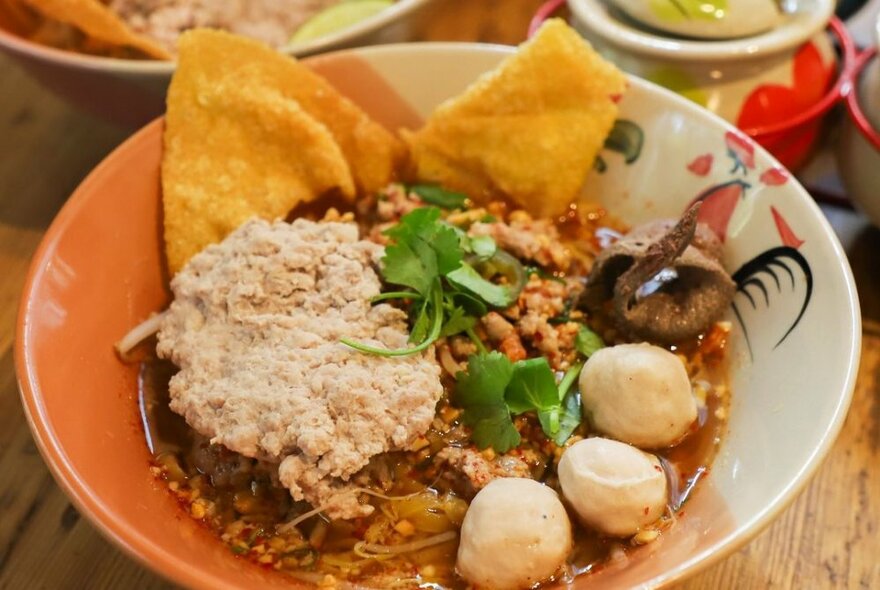 A bowl of Thai food including rice and balls.