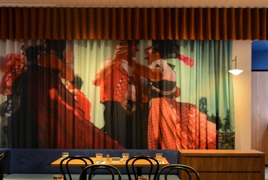 Dinner table seating with image of Swiss couples dancing wearing traditional dress, screened into curtains.