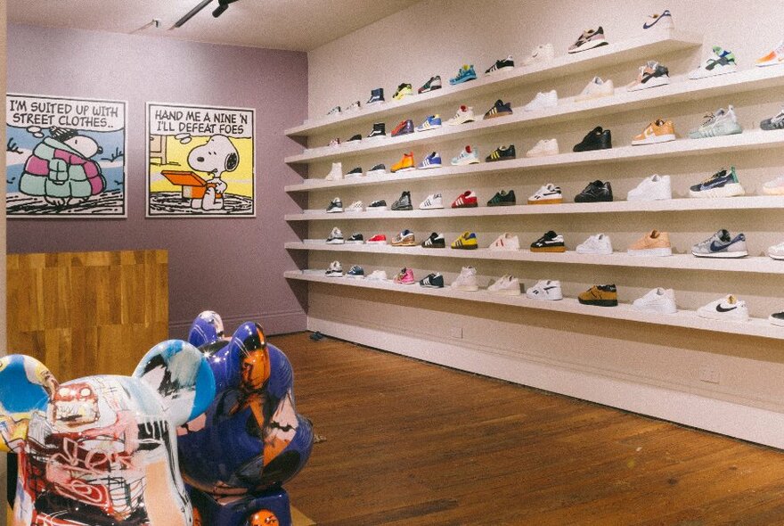 A shop corner with racks of sneakers, painted teddy statues and Snoopy comic posters on the wall.