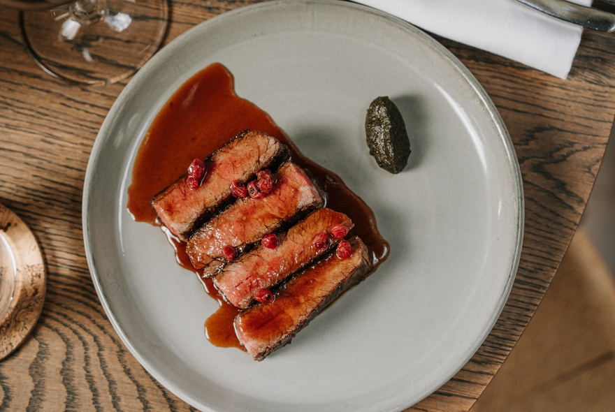 Looking down on a plate with four slices of fish with a red sauce. 