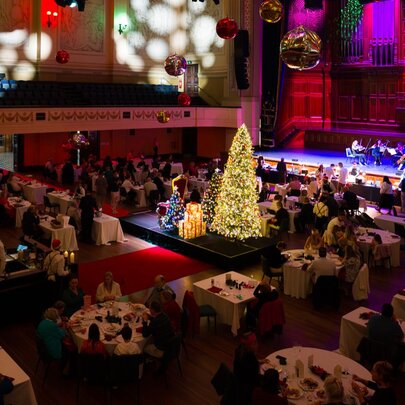 The inside of Melbourne's Town Hall, set with tables and chairs plus a glowing Christmas tree for a Christmas buffet.