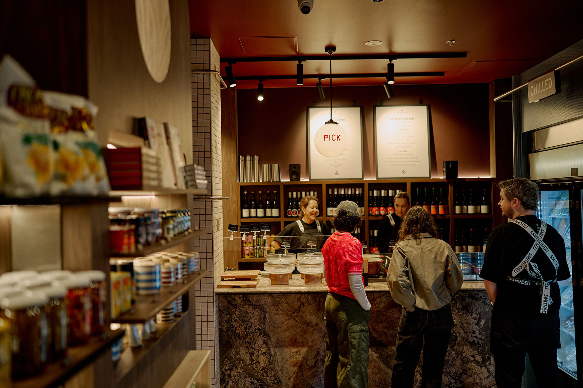 People lining up at the counter of a deli.