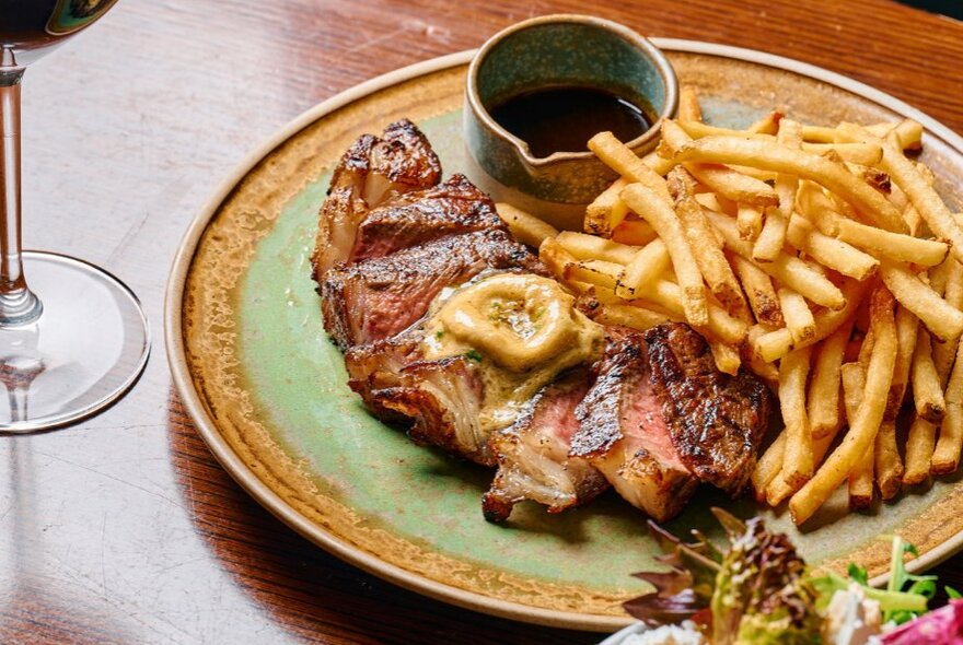 A steak with butter, chips, gravy and wine.