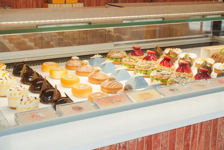 Full patisserie window with many varieties of cakes on display. 