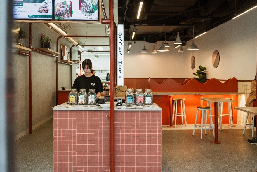 Cafe interior with a tiled central bar area with juices and bar seating.