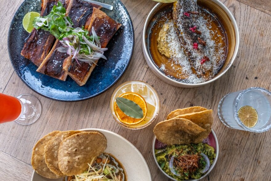 Array of Mexican dishes and drinks on a wooden table.