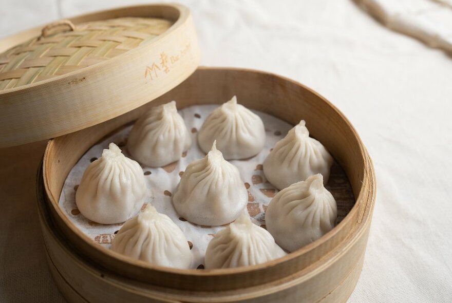 A bamboo steamer basket filled with xiao long bao dumplings.