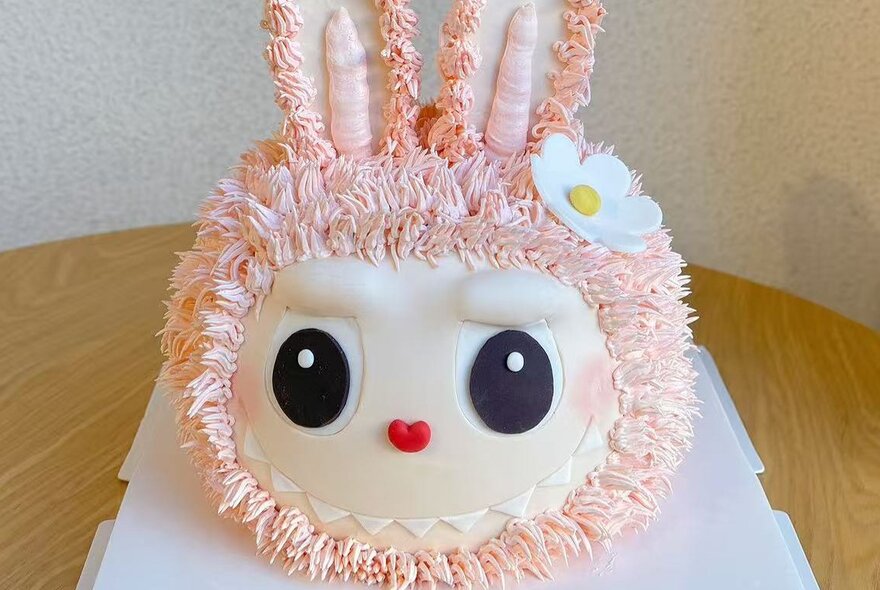 A cake in the shape of a pink Labubu doll face. 