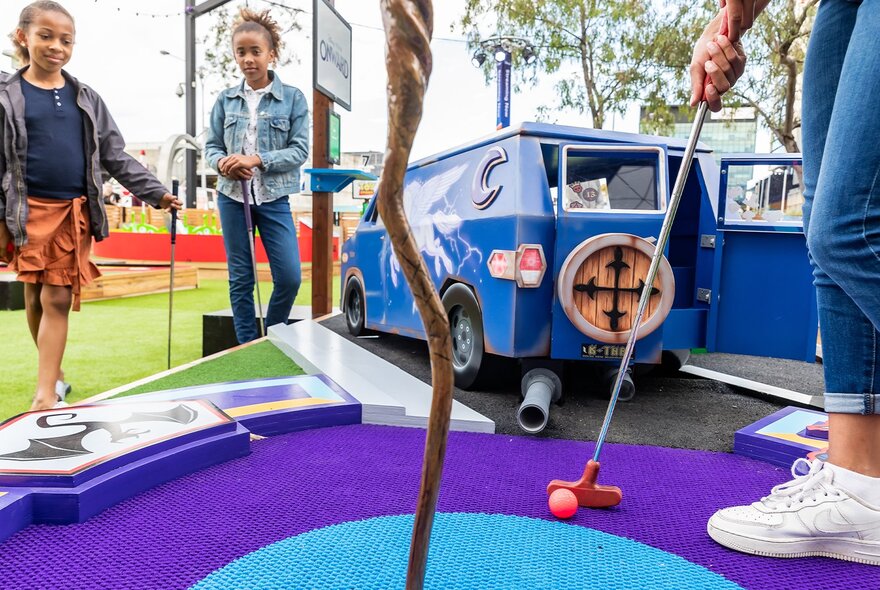 People putting on a brightly coloured minigolf course.