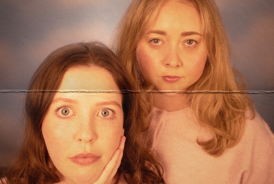 Faded picture of two women with a fold mark down the middle. 