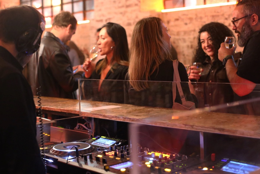 People drinking wine at a bar in a brick-walled venue.