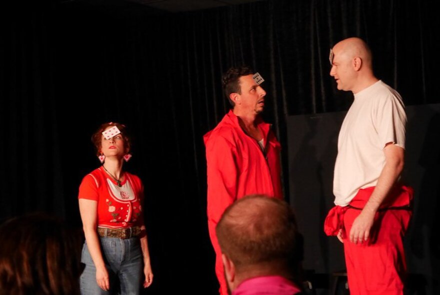 Three actors on stage performing an improvised theatre routine.