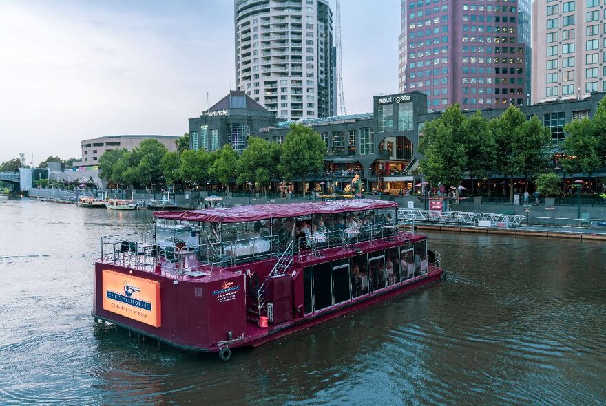 A burgundy coloured cruise boat on the Yarra River in Melbourne. 