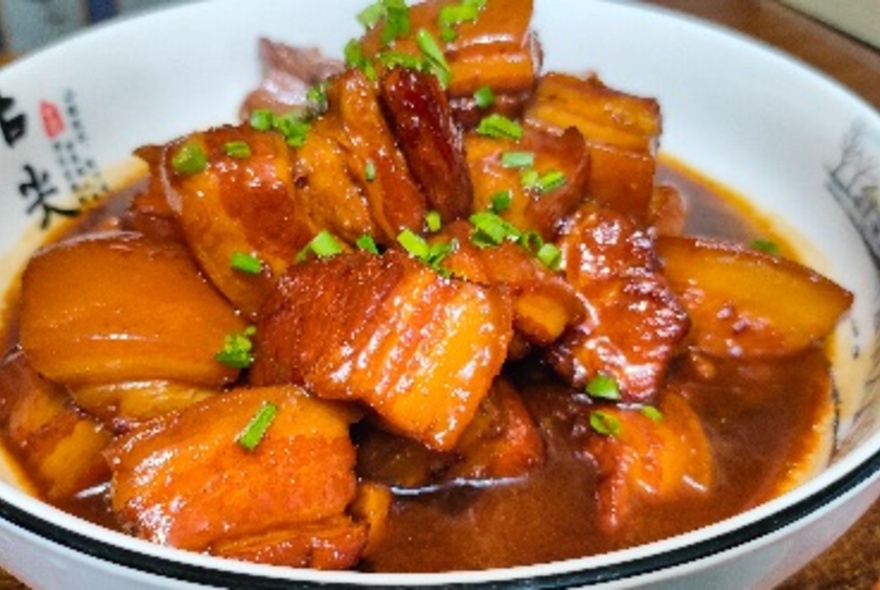 An Asian dish of braised pork in an orange sauce.