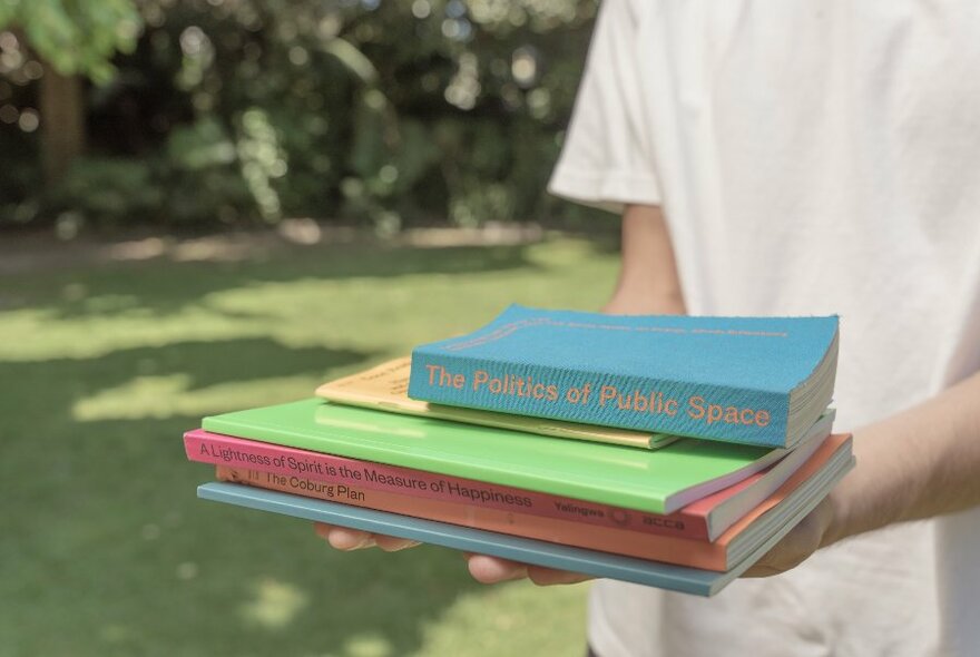 Person holding a small pile of books.