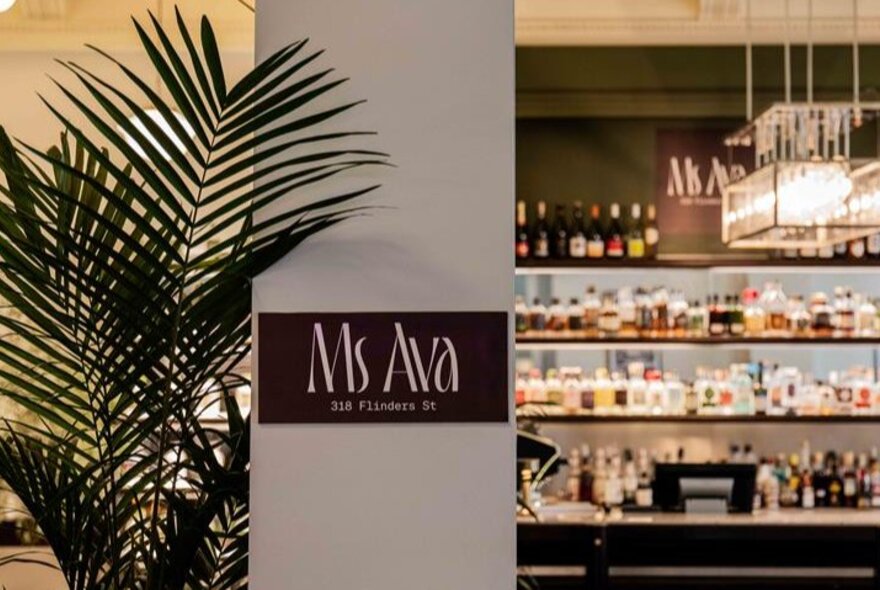 The interior of Ms Ava bar with a sign on the column and a fern. 