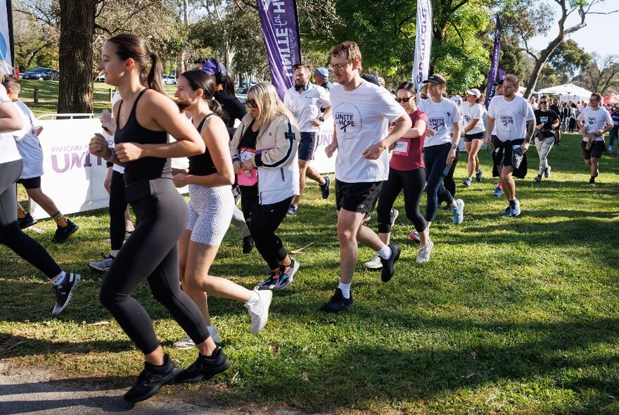 Teams of runners passing banners in a grassy parkland setting.