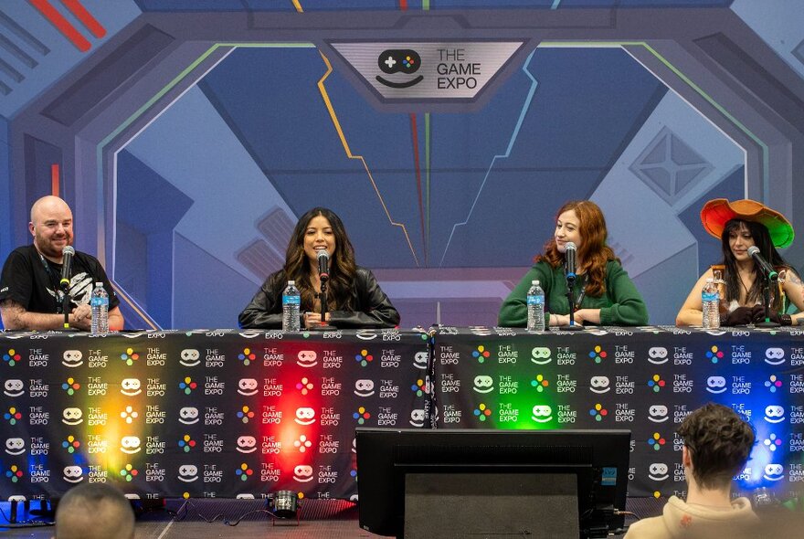 Four panellists on a stage at The Games Expo talking to an audience.