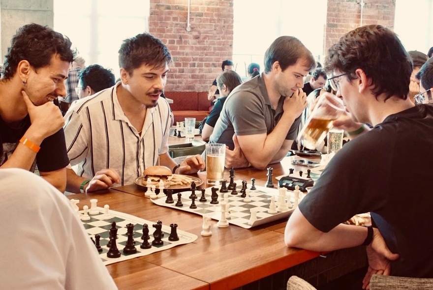 People playing chess at a table in a pub like venue.