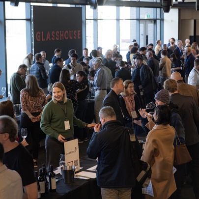 A wine tasting event with numerous attendees browsing booths.