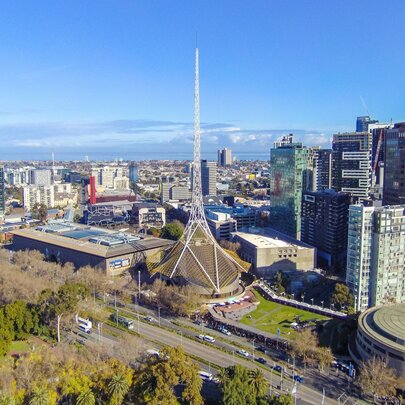 Arts Centre Melbourne with winter trees and blue sky, surrounded by city buildings.