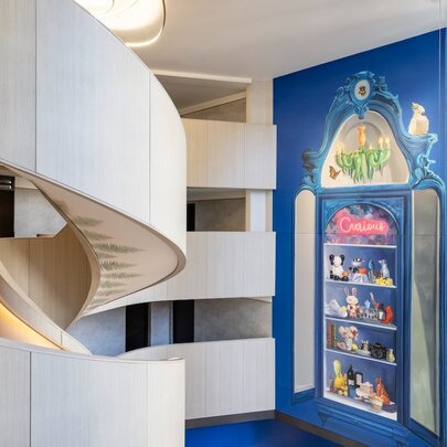 White spiral staircase at Hotel Indigo, with a blue feature wall and a painted mural.