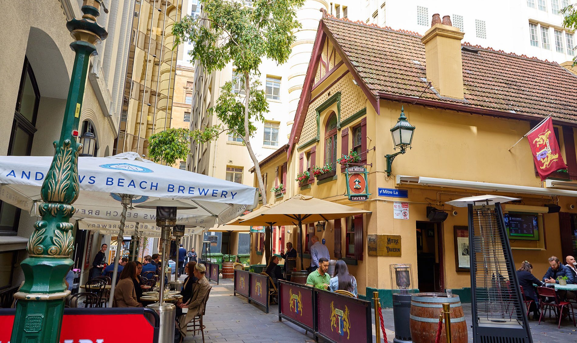 An heritage pub with lanterns and outdoor seating in a city laneway. 