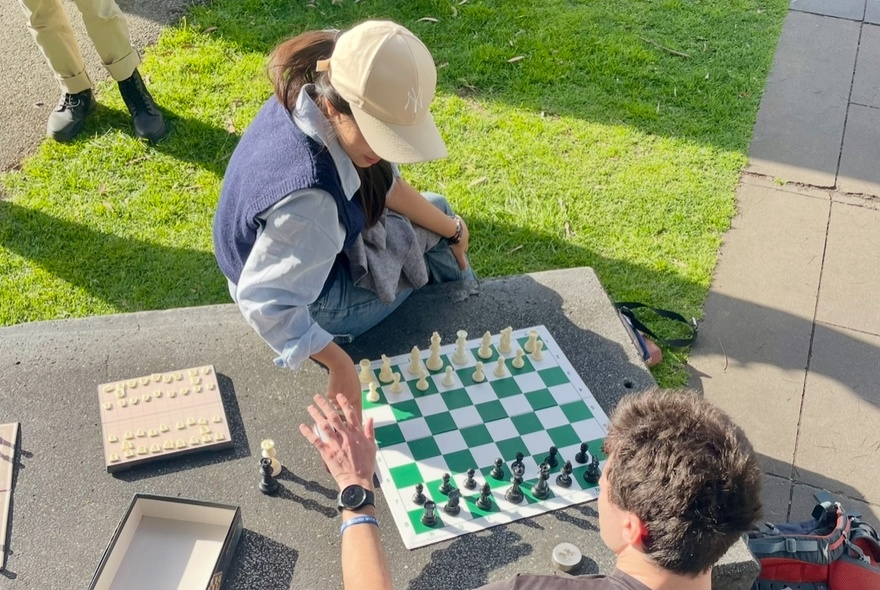 Two people playing chess outside.