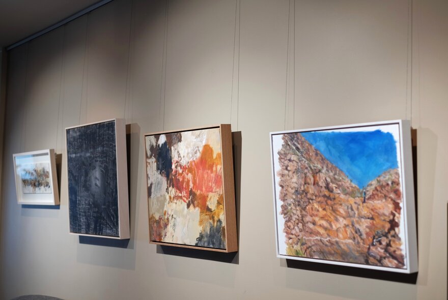 Artworks of Australian landscapes hanging on a grey wall.