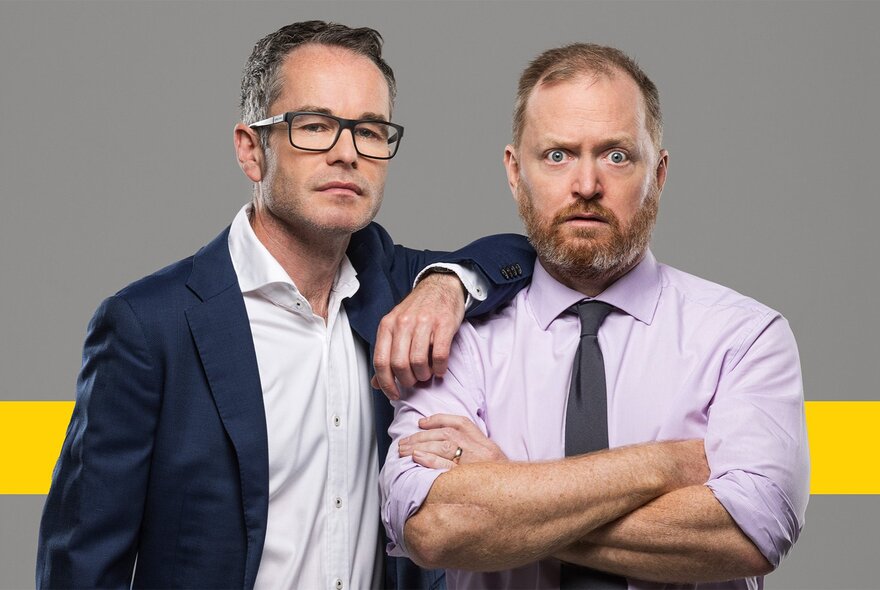 Two men, one with glasses resting his arm on another's shoulder, the other with a beard and crossed arms looking perplexed.
