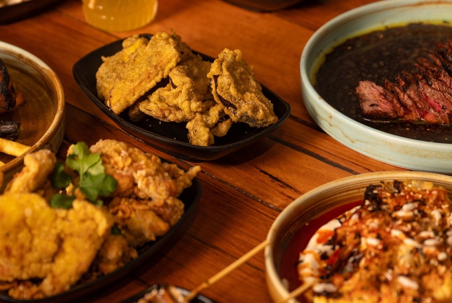 A delicious-looking spread of Asian dishes presented on a wooden table.