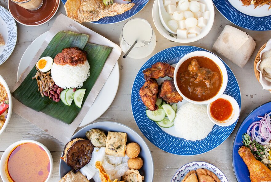 Looking down on a table spread with a variety of Asian dishes and drinks.