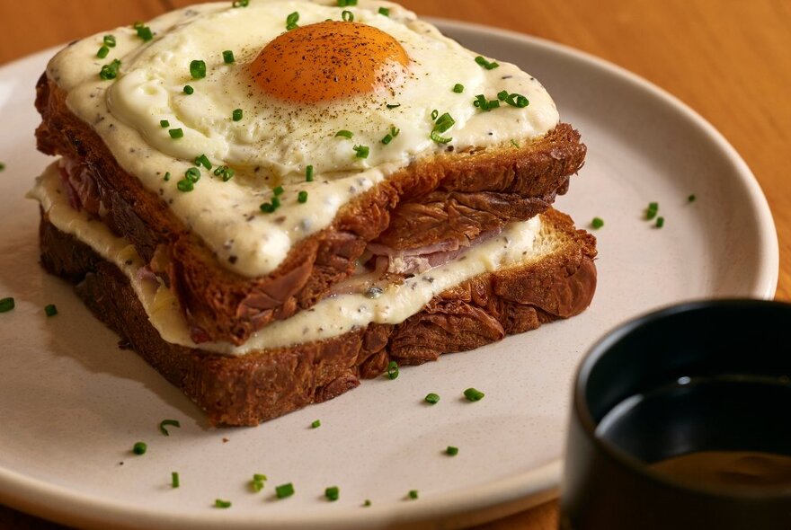 A double layered fried egg on two slices of toast on a white plate.