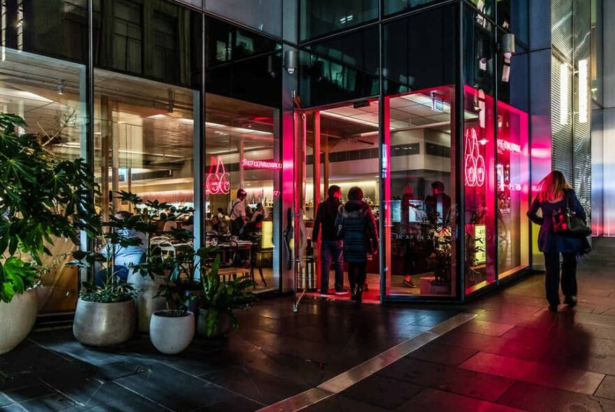 People walking past a restaurant at night