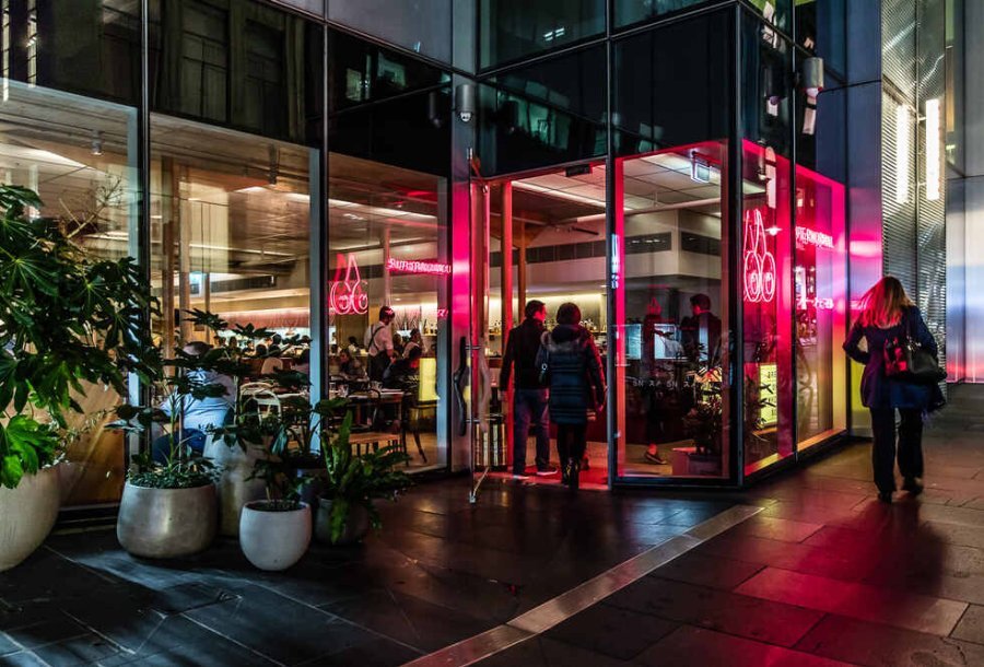 People walking past a restaurant at night