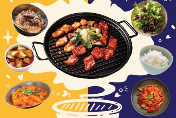 A sizzling hot plate of BBQ meats surrounded by side dishes including kimchi and rice.