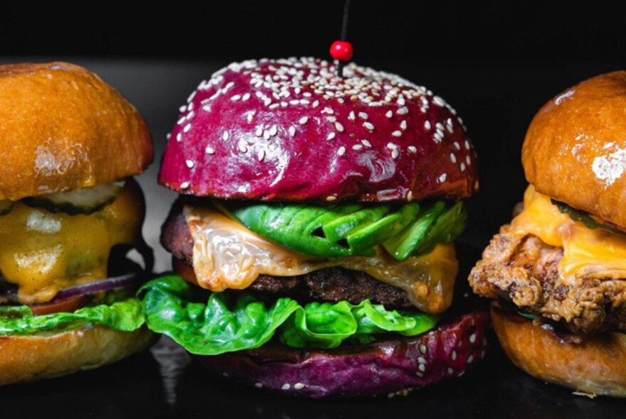 A beef burger with a purple coloured brioche bun, lettuce and melted cheese.