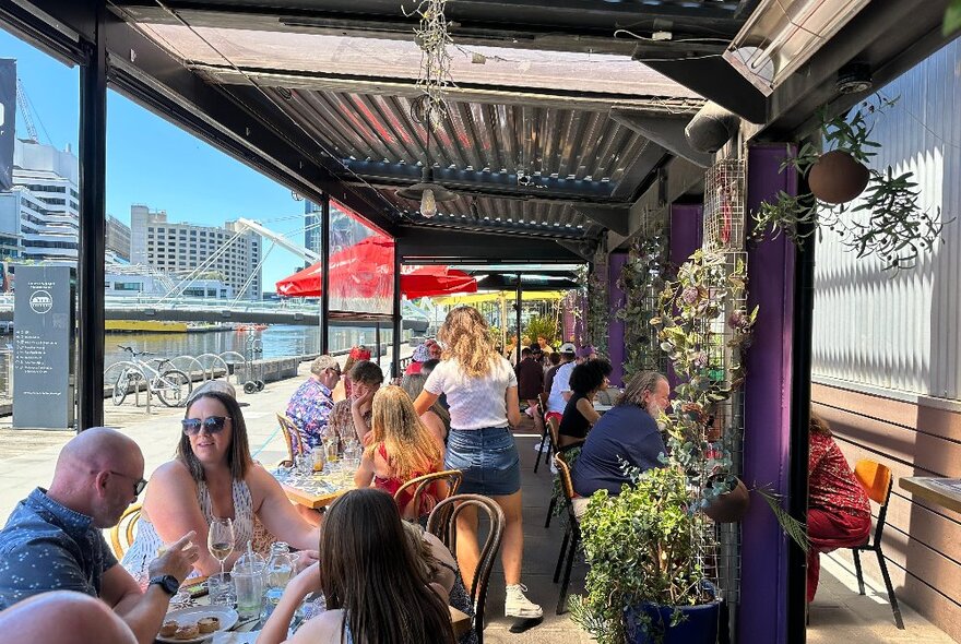 People seated at tables on an outdoor balcony with city views.