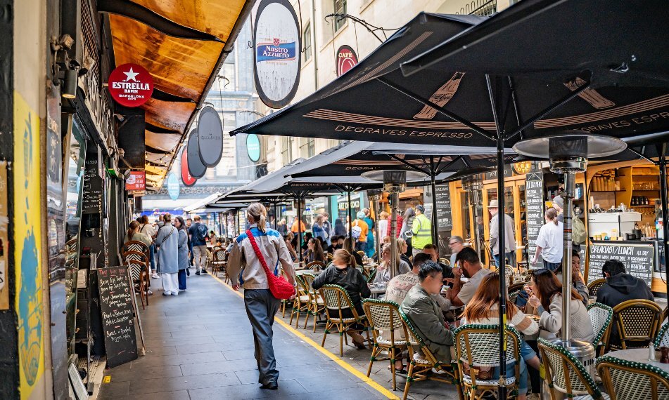 A busy laneway with people dining outdoors.