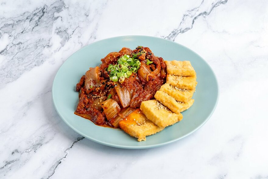 Pork kimchi tofu on a blue plate on a marble table. 