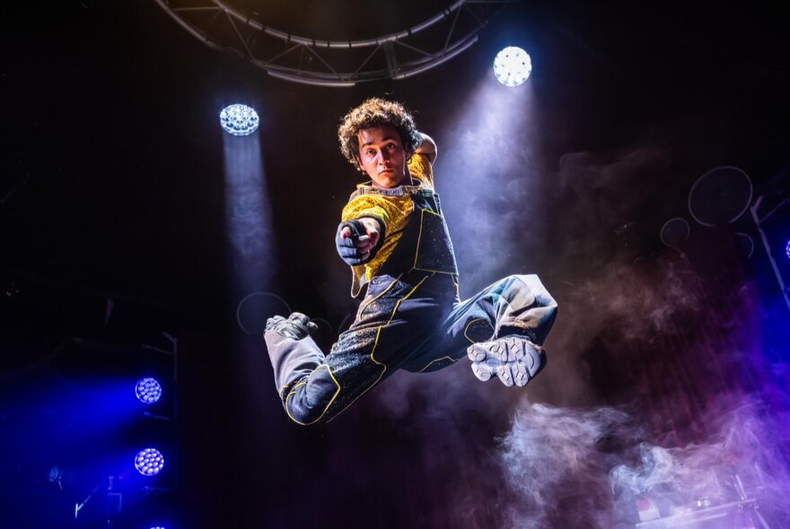A children's circus performer jumping high with his knees bent.