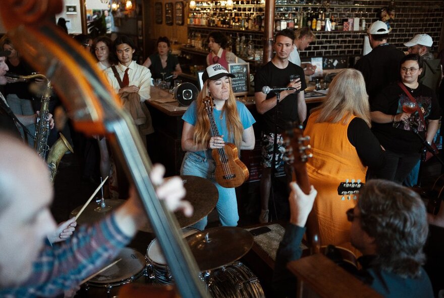 People in a bar setting, some with instruments, others just watching on. 