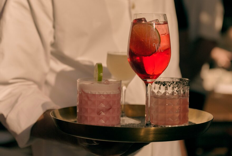 A waiter carrying a tray of cocktails.